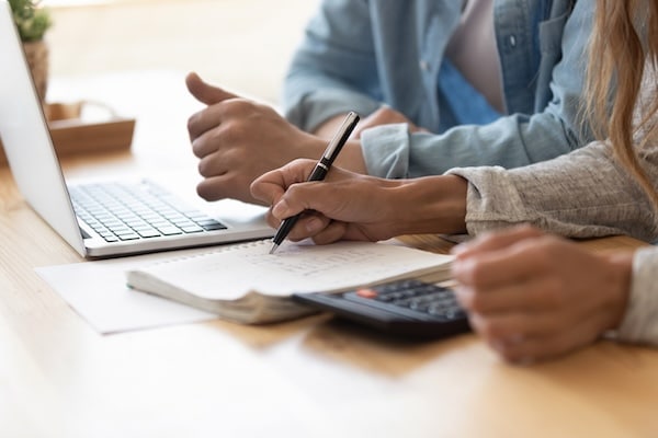 Close up spouses calculating family budget paying online using laptop
