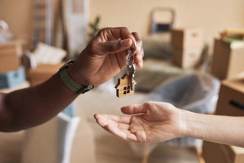 Hand of young African American agent passing key to new owner of apartment